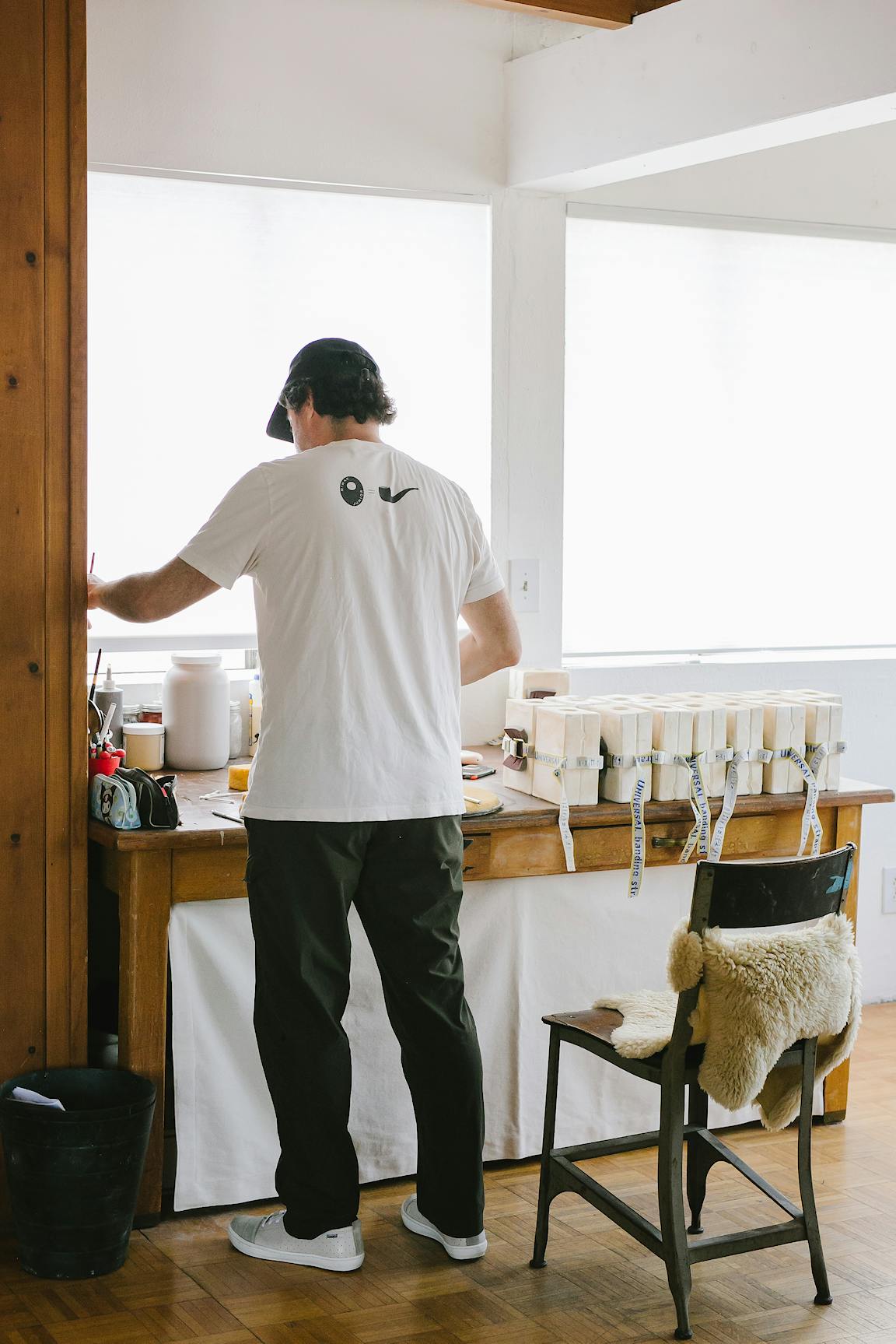 A person stands at a work table in a ceramic studio.